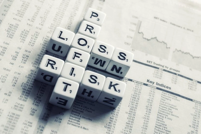 Set of dice spelling profit, loss and risk on a financial newspaper