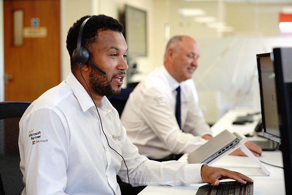 IT sales engineer at a desk on the phone with a head-set to a customer in Bristol