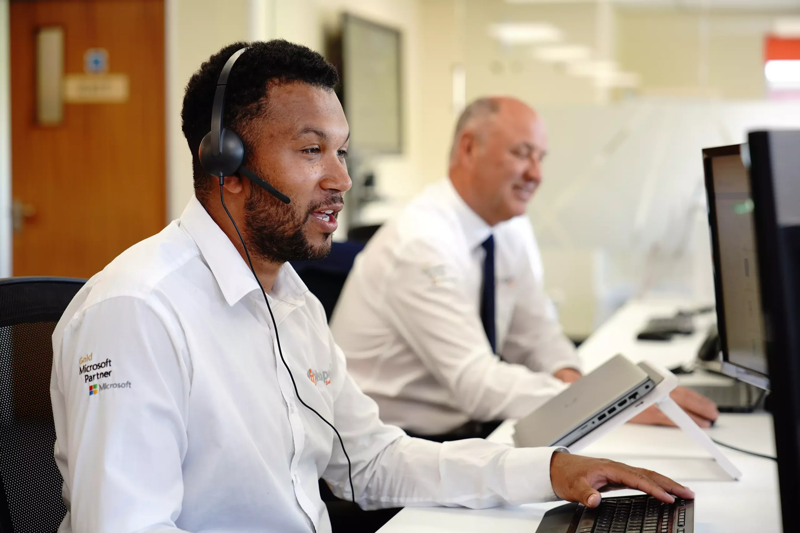 Impact IT Solutions sales engineer at a desk on the phone with a head-set to a customer in the South West